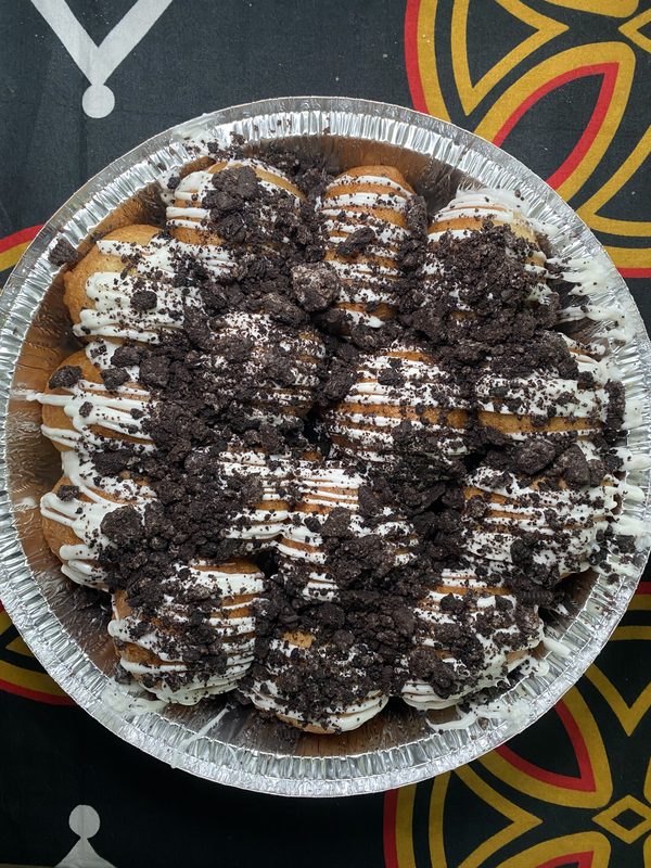 Cookies and cream beignets with white chocolate drizzle and Oreo crumble